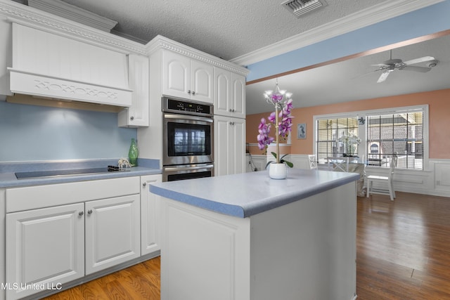 855 Dove Blvd, Bay Saint Louis, MS 39520 - kitchen featuring black electric stovetop, wainscoting, white cabinets, ornamental molding, and light wood-style floors