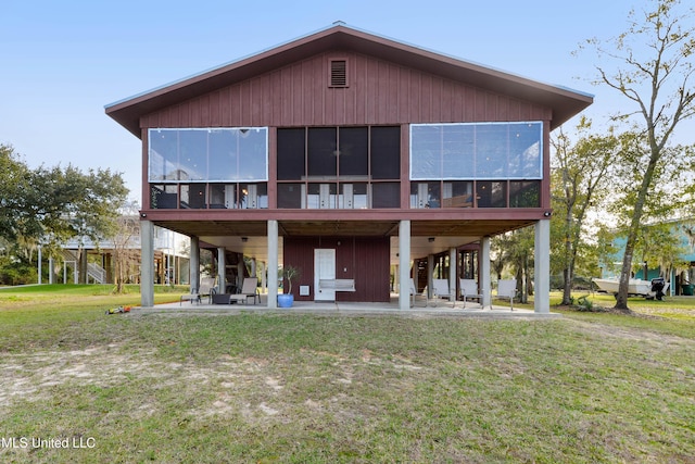 back of house featuring a sunroom, a patio area, and a yard