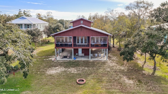 back of property with a patio area, a sunroom, a yard, and a fire pit