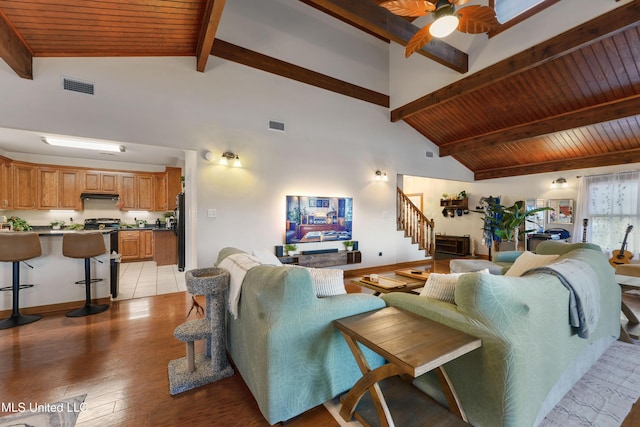 living room with ceiling fan, beam ceiling, light wood-type flooring, and wooden ceiling