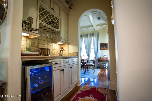 bar featuring coffered ceiling, cream cabinets, wine cooler, beamed ceiling, and light hardwood / wood-style floors