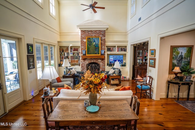 living room with plenty of natural light, wood-type flooring, a fireplace, and a towering ceiling