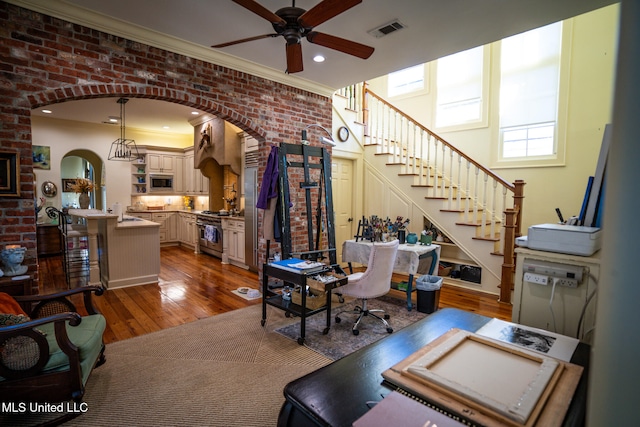 office space with crown molding, ceiling fan, brick wall, and dark hardwood / wood-style floors