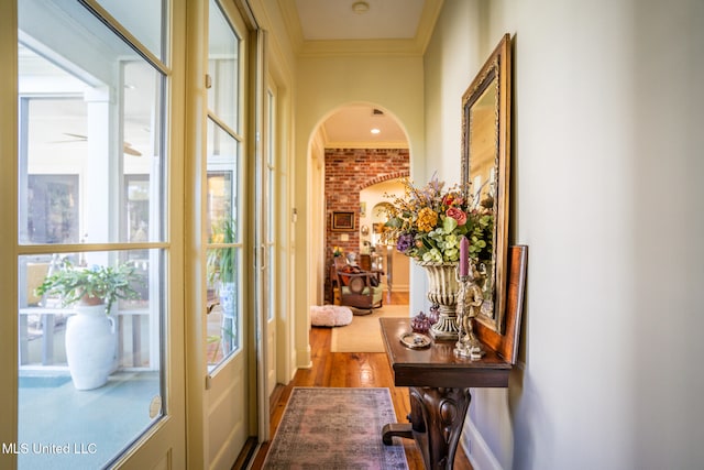 entryway with a wealth of natural light, wood-type flooring, brick wall, and ornamental molding