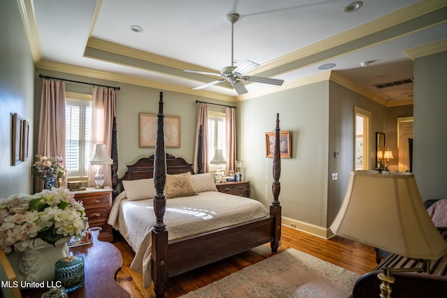 bedroom featuring a raised ceiling, ceiling fan, wood-type flooring, and ornamental molding