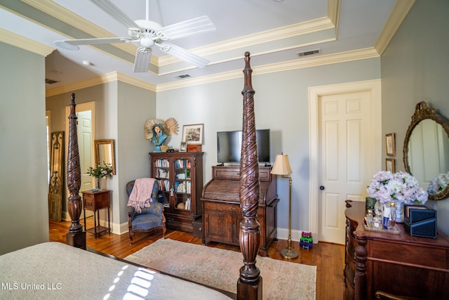 bedroom featuring ceiling fan, dark hardwood / wood-style flooring, ornamental molding, and a tray ceiling