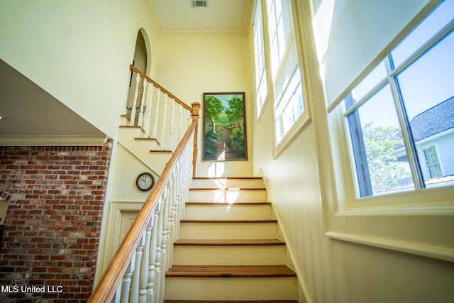 stairs featuring crown molding and a high ceiling