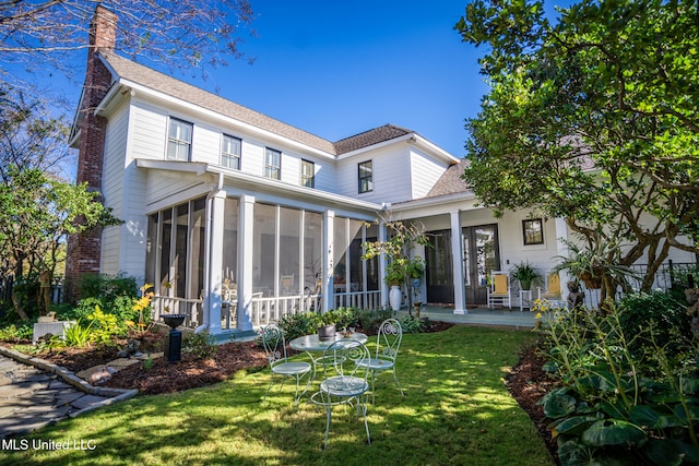 rear view of house with a sunroom, a patio area, and a yard