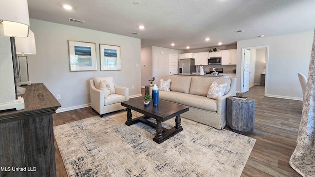 living room with visible vents, baseboards, recessed lighting, wood finished floors, and a textured ceiling