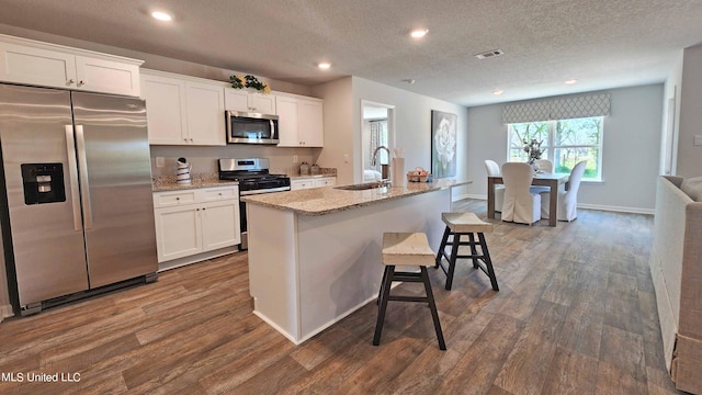 kitchen with dark wood-style floors, visible vents, a sink, appliances with stainless steel finishes, and white cabinetry