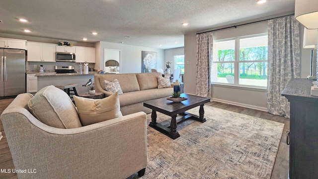 living area with recessed lighting, a textured ceiling, and wood finished floors