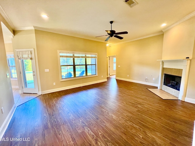 unfurnished living room with ornamental molding, wood-type flooring, and a tiled fireplace