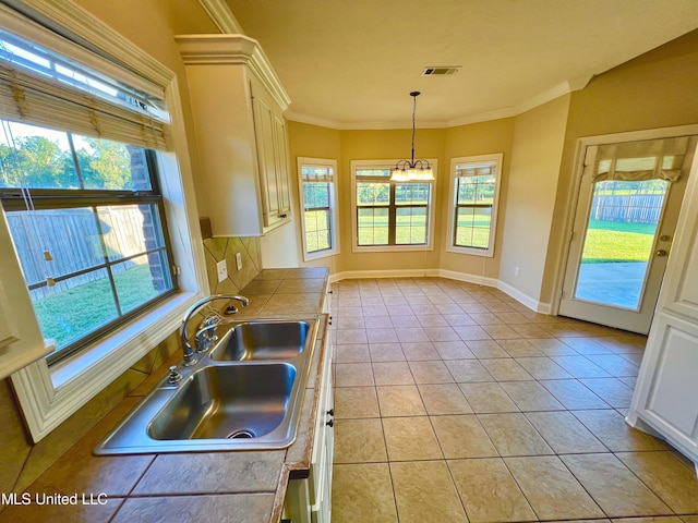 kitchen featuring tile counters, decorative light fixtures, sink, plenty of natural light, and light tile patterned flooring