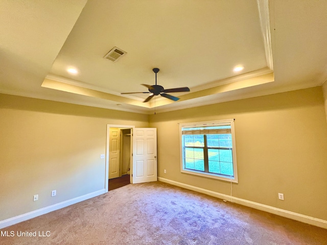 unfurnished bedroom featuring ceiling fan, a tray ceiling, crown molding, and carpet flooring