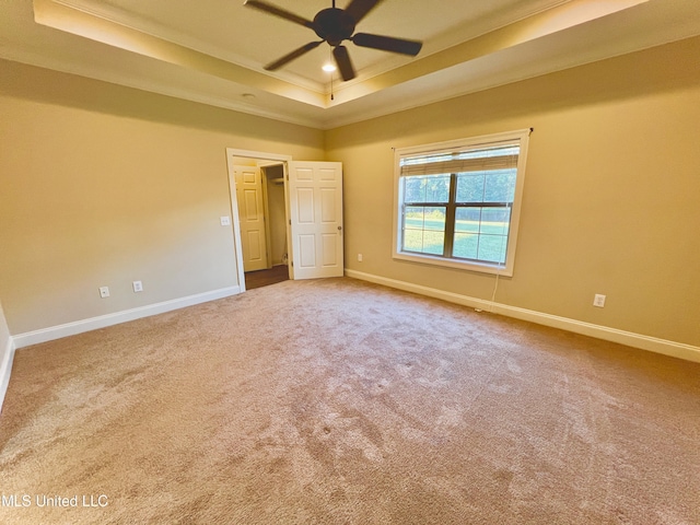 carpeted spare room featuring ceiling fan, a tray ceiling, and ornamental molding