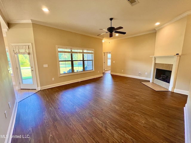 unfurnished living room featuring ceiling fan, a tiled fireplace, dark wood-type flooring, and crown molding