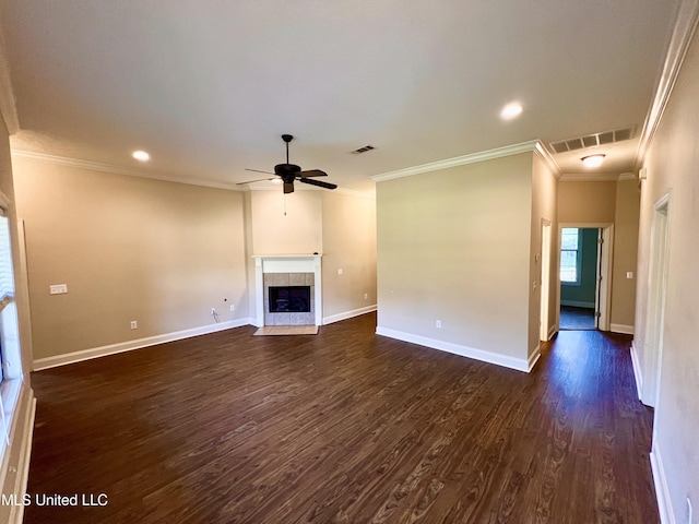 unfurnished living room with ceiling fan, dark hardwood / wood-style flooring, ornamental molding, and a tiled fireplace