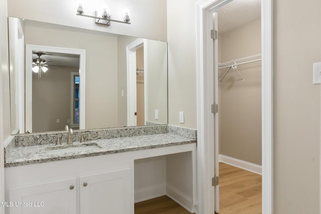 1304 Estelle St, Hattiesburg, MS 39402 - bathroom featuring wood finished floors, vanity, a walk in closet, and a ceiling fan