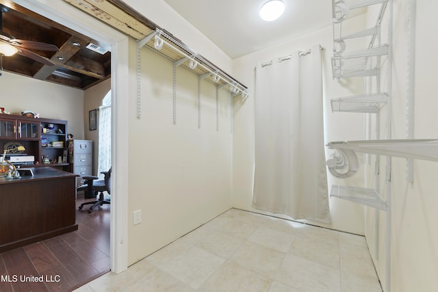 spacious closet with visible vents, ceiling fan, coffered ceiling, and beamed ceiling