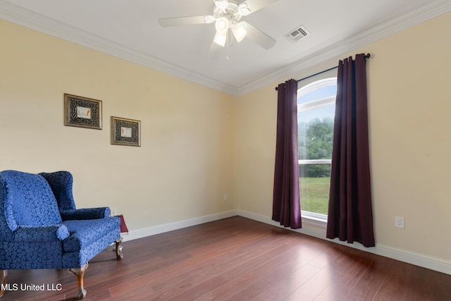 living area featuring wood finished floors, ceiling fan, baseboards, visible vents, and crown molding