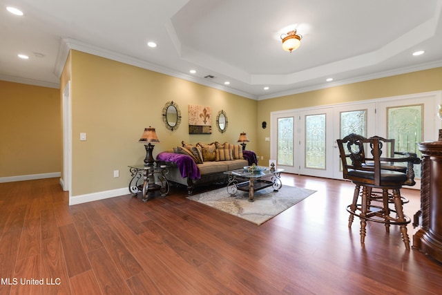 living room with recessed lighting, a tray ceiling, crown molding, baseboards, and wood finished floors