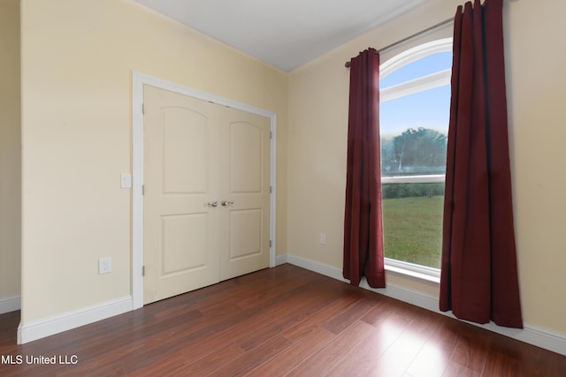 empty room with plenty of natural light, dark wood finished floors, and baseboards