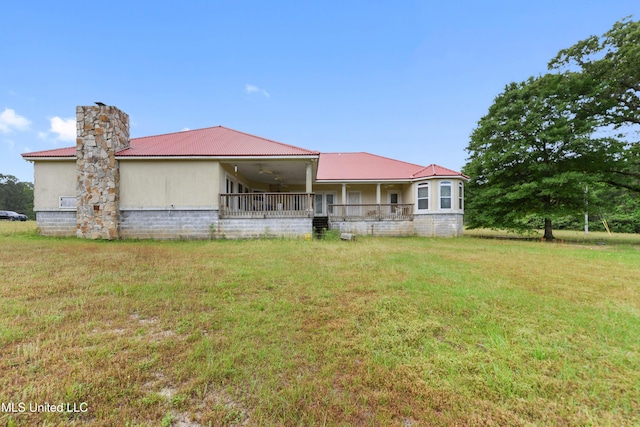 rear view of property with a chimney, covered porch, ceiling fan, metal roof, and a lawn