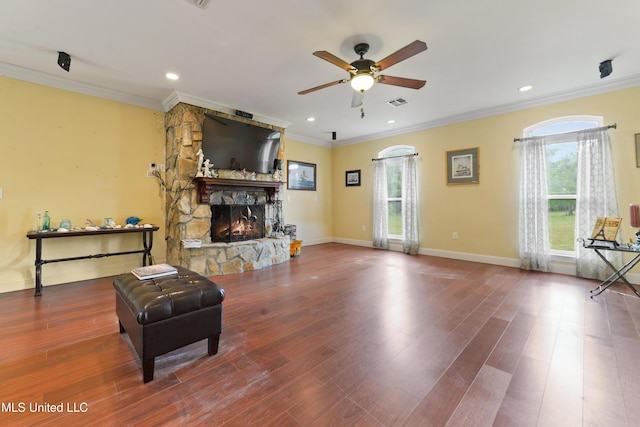 living area with crown molding, visible vents, recessed lighting, a ceiling fan, and a stone fireplace
