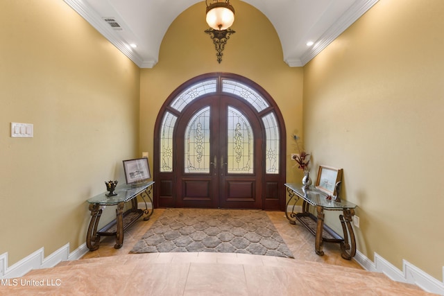 tiled foyer entrance with visible vents, baseboards, ornamental molding, and arched walkways