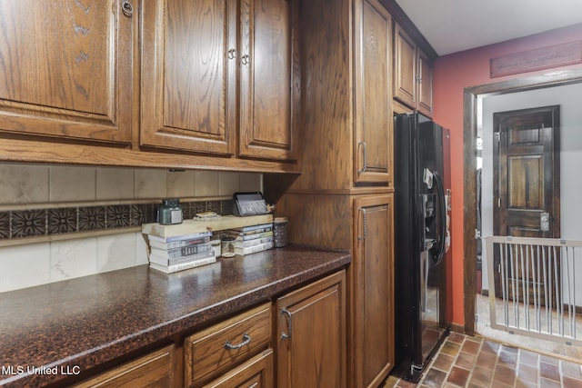 2213 N St, Gulfport, MS 39507 - kitchen featuring black refrigerator with ice dispenser, decorative backsplash, baseboards, brick patterned floors, and dark countertops