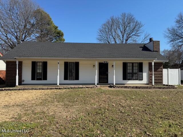 ranch-style home with covered porch, a chimney, a front yard, and fence