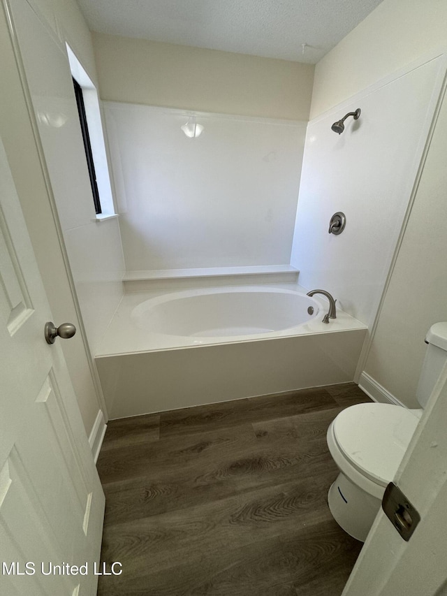 full bath featuring a garden tub, wood finished floors, and toilet