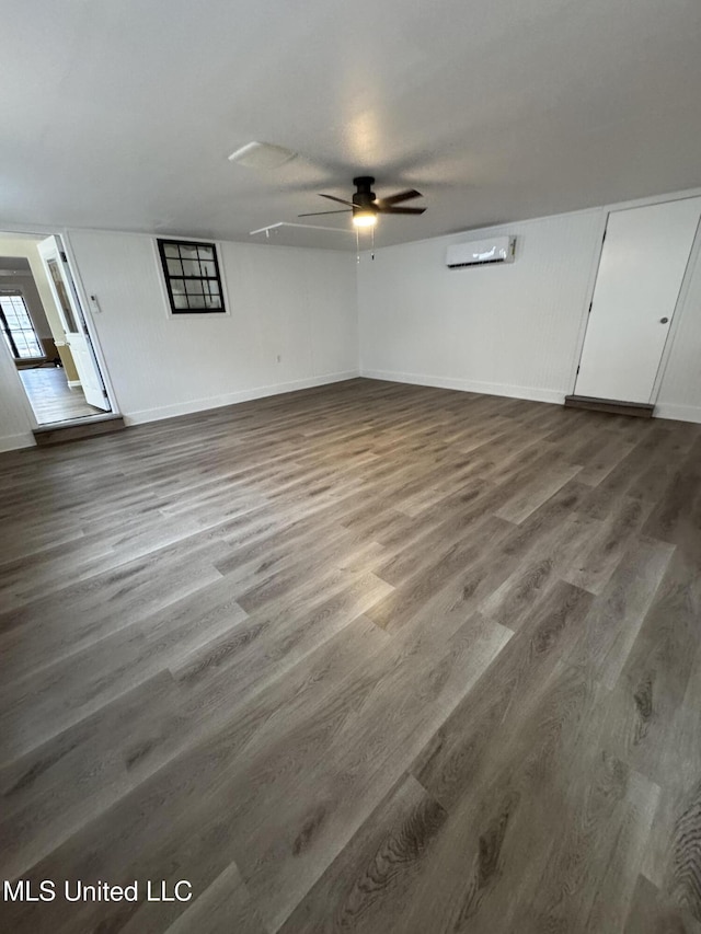 interior space featuring a wall mounted air conditioner, ceiling fan, baseboards, and wood finished floors