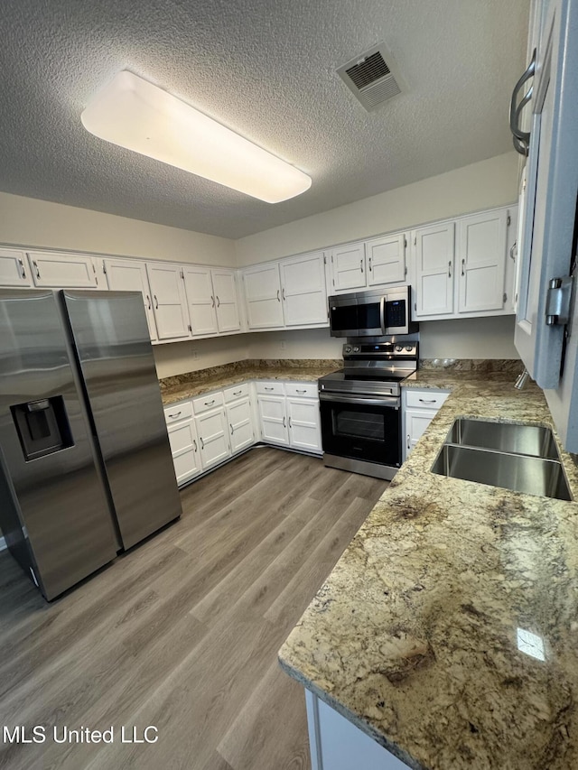 kitchen featuring light wood finished floors, appliances with stainless steel finishes, visible vents, and white cabinets