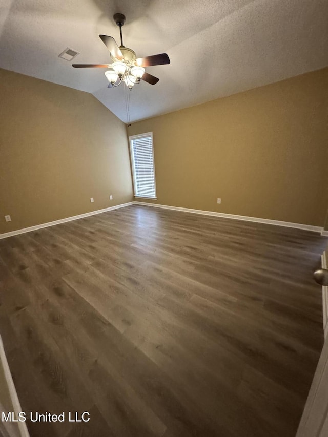 spare room featuring visible vents, baseboards, a ceiling fan, wood finished floors, and vaulted ceiling