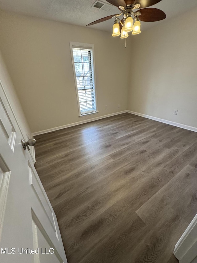 spare room featuring dark wood-style floors, baseboards, and a textured ceiling