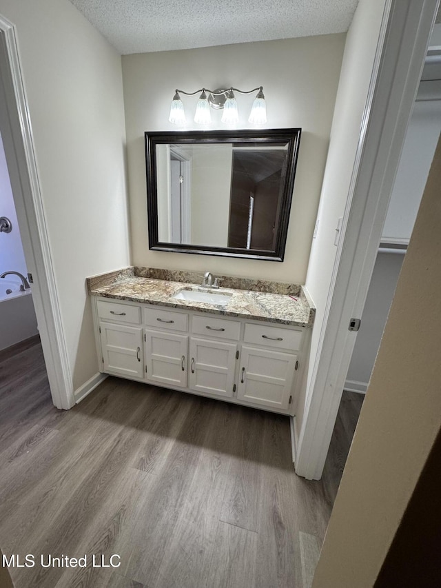 bathroom featuring a textured ceiling, wood finished floors, vanity, and baseboards