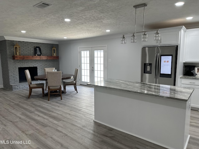 dining room featuring a fireplace, french doors, a textured ceiling, and light hardwood / wood-style flooring