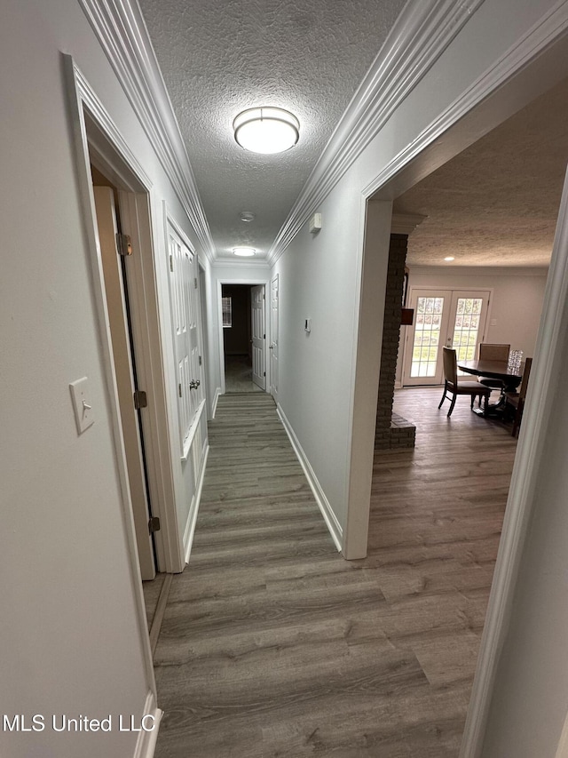 hallway with hardwood / wood-style flooring, ornamental molding, a textured ceiling, and french doors