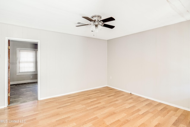 unfurnished room featuring light hardwood / wood-style flooring, wooden walls, and ceiling fan