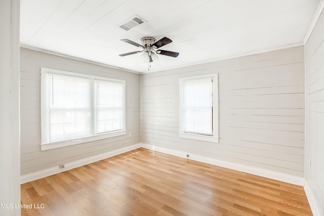 spare room featuring ceiling fan, wood walls, wood-type flooring, and crown molding