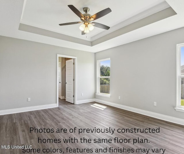 empty room with crown molding, hardwood / wood-style flooring, a tray ceiling, and ceiling fan