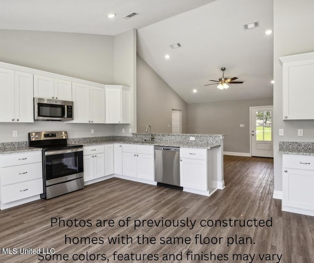 kitchen with appliances with stainless steel finishes, sink, dark hardwood / wood-style flooring, kitchen peninsula, and white cabinetry