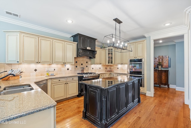 kitchen featuring appliances with stainless steel finishes, sink, light wood-type flooring, a center island, and hanging light fixtures