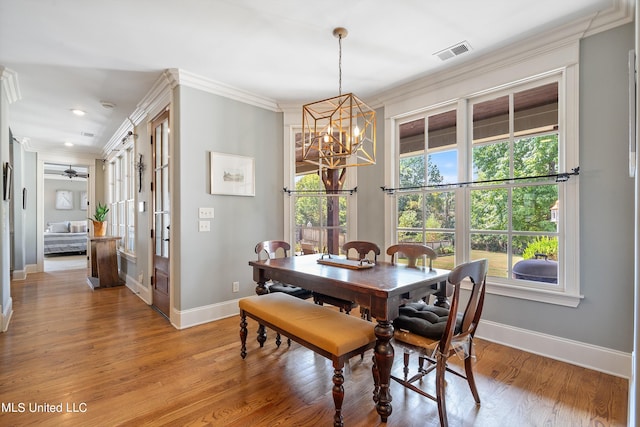 dining space featuring crown molding, light hardwood / wood-style flooring, and ceiling fan with notable chandelier