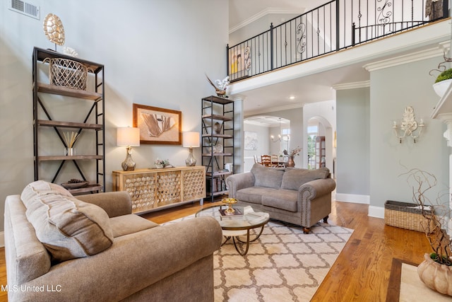 living room with a chandelier, crown molding, hardwood / wood-style flooring, and a high ceiling