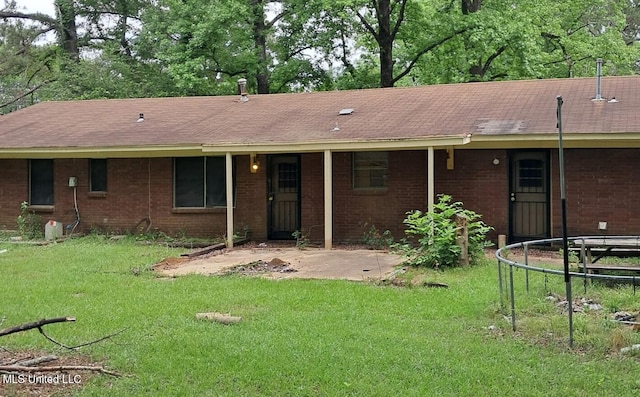 2943 Suncrest Dr, Jackson, MS 39212 - back of house with a lawn, a trampoline, brick siding, and a shingled roof