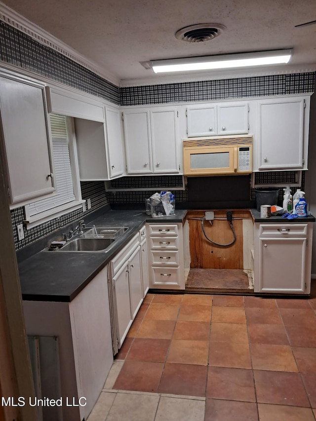 2943 Suncrest Dr, Jackson, MS 39212 - kitchen featuring a sink, white microwave, dark countertops, and white cabinetry