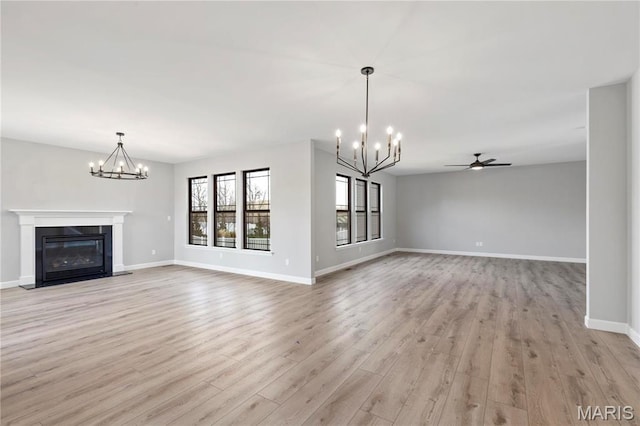 1 Hadleigh, Windsor Park, Lake St Louis, MO 63367 - unfurnished living room featuring a chandelier, a fireplace with flush hearth, light wood-type flooring, and baseboards