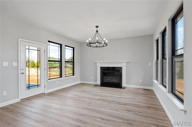 1 Hadleigh, Windsor Park, Lake St Louis, MO 63367 - unfurnished living room with healthy amount of natural light, light wood finished floors, a chandelier, and baseboards